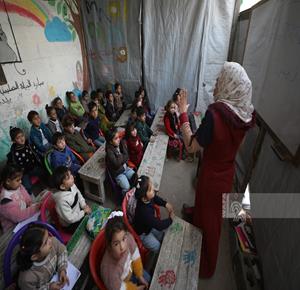 עזה – ילדים עקורים מקבלים שיעורים בתוך אוהל במחנה אל־ירמוכ בעזה, לאחר שרוב בתי הספר נהרסו וחלקם הוסבו למרכזי מחסה בעקבות המלחמה.
