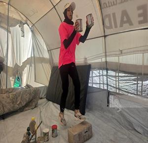 מאמנת הכושר אימאן אל־מור'ייר מתאמנת בתוך אוהלה בחאן יונס שבדרום רצועת עזה. היא משתמשת בקופסאות מזון ריקות ובפסולת אחרת להכנת מתקני אימון.