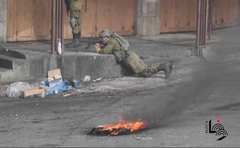 צלף מחיילי הכיבוש היהודי בחברון מכוון את נשקו למפגינים נגד הכיבוש.