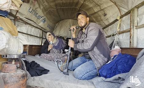 סאמי אבו סעדה מטפל באמו החולה בתוך עגלה בתנאי עקירה קשים בחאן יונס, דרום רצועת עזה.